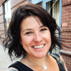 Cala Coats smiling at the camera, short dark hair, head-and-shoulders
