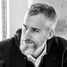Man looking to the left, beard, short hair, black-and-white head-and-shoulders image 