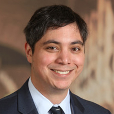 Man smiling at the camera, wearing a coat and tie