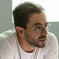 Man in white T-shirt looking toward the right, wearing glasses