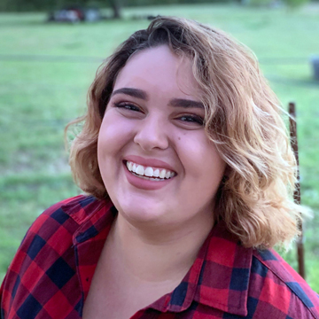 Head-and-shoulders: Cassandra smiling at the camera, short blonde wavy hair
