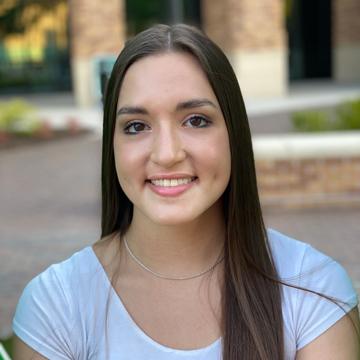 Head-and-shoulders: Katherine smiling at the camera, long dark hair, white shirt