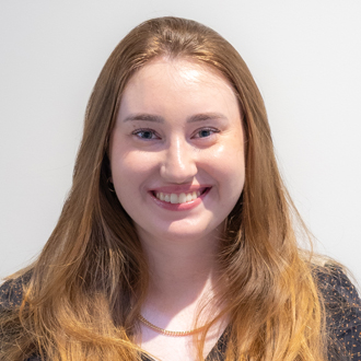 Julia is facing forward and smiling. She has long blonde-brown hair 