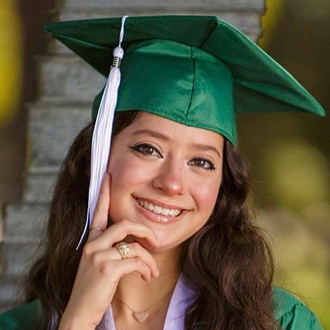 Isabel is facing forward and smiling. She wears a green cap and gown.