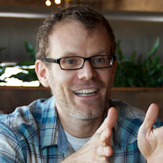 Man wearing glasses and a blue shirt gesturing with his hands