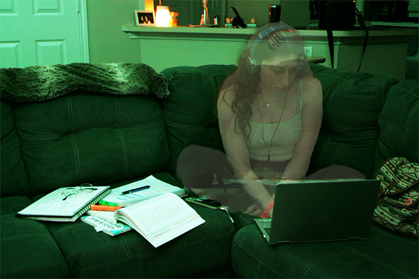 Person looking at a laptop, sitting on a green couch in a living room with low light