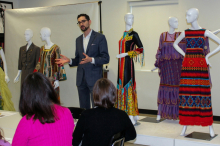 Image of the Director of the Onstead Institute speaking to a group of workshop participants with six mannequins in background wearing bright colored dresses