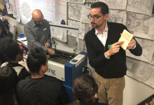 Image of Onstead Institute Director providing an instructional demonstration of a laser cutter to a group of students.